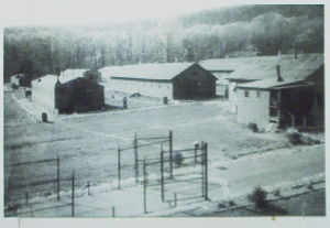 A photo showing some of the barracks where prisoners were housed. The entrance gate structure is in the foreground and the prisoners mess hall is on the right. Via the Cumberland County Historical Society.