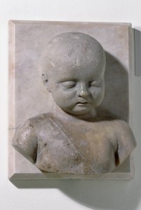 Marble bust of a sleeping child wearing crepundia (amulets and charms) on a cord across his chest. © The Trustees of the British Museum.
