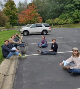 Photo shows ALLARM and PLEWA team sitting in a parking lot for their meeting.