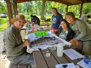 Natalia sits with Stream Team members as they work on identifying macroinvertebrates.