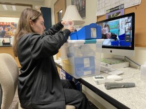 Kailey holds a beaker up to the camera to allow volunteers to watch the process.