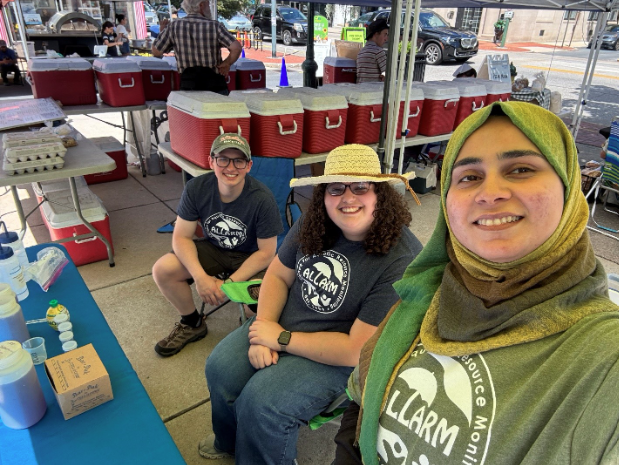 A selfie of Hakeema, Alyssa, and Ryan taken in their booth at Farmers on the Square in.