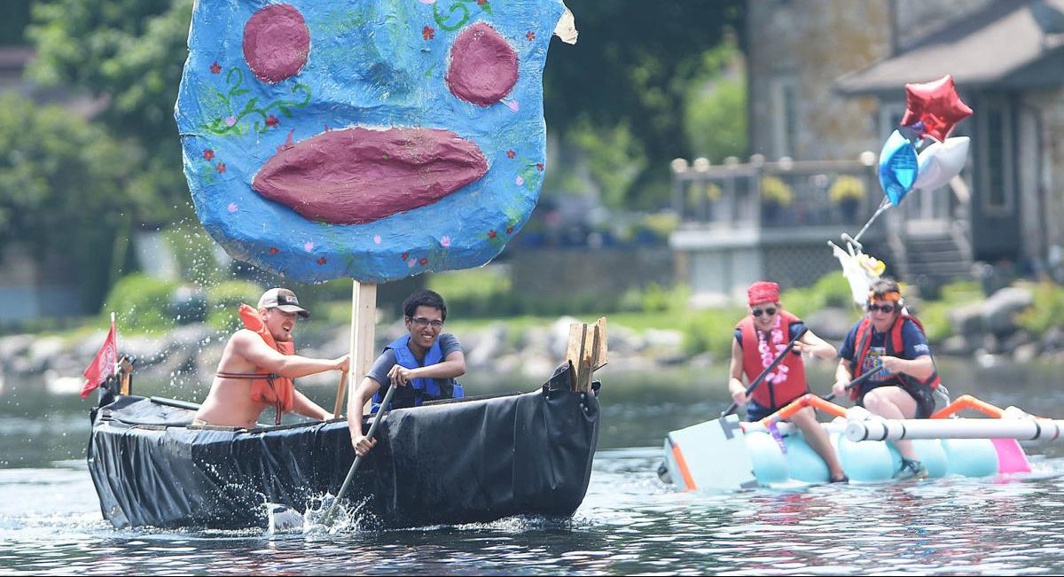 Two people rowing a boat with a giant blue face