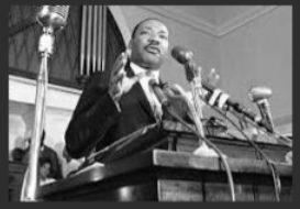 Martin Luther King, Jr. speaking at a podium with many microphones. 