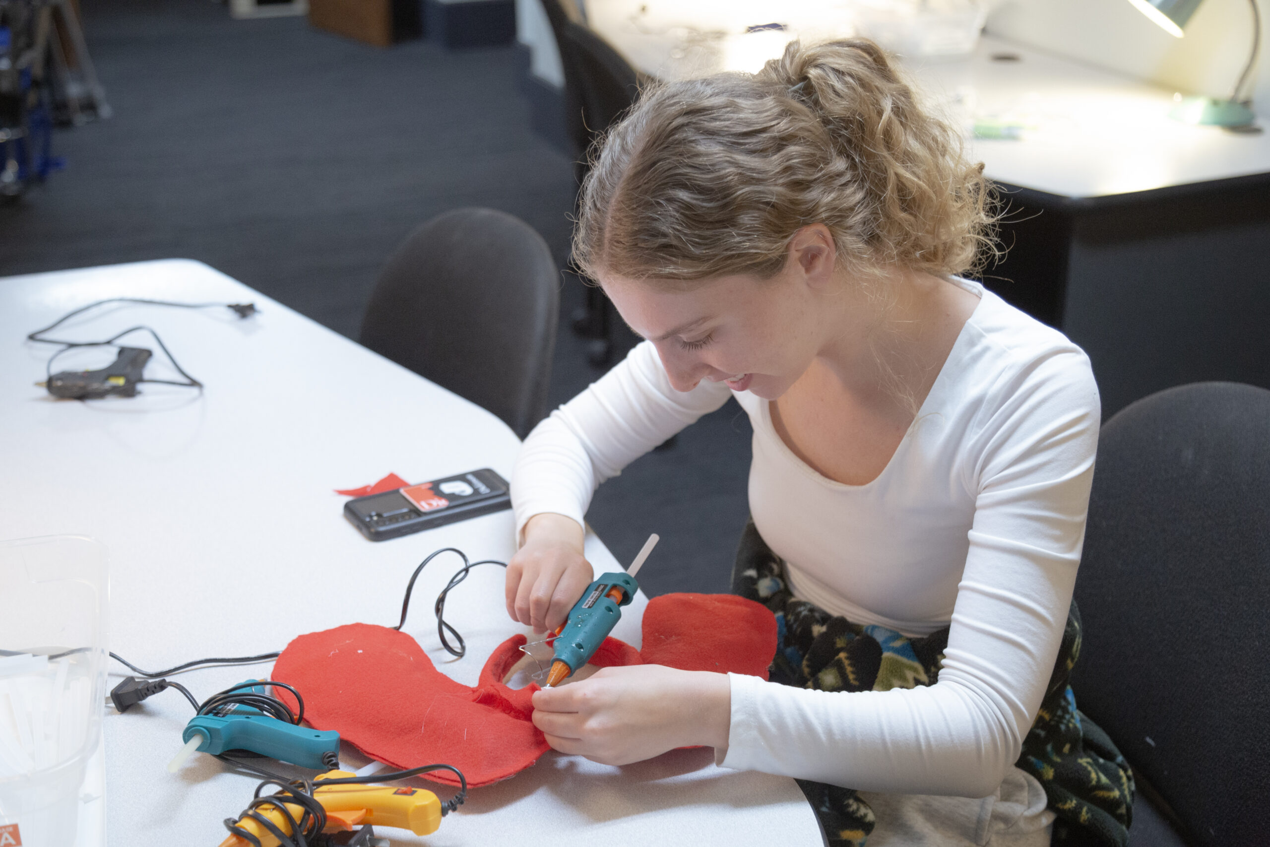 student using a hot glue gun on a piece of felt